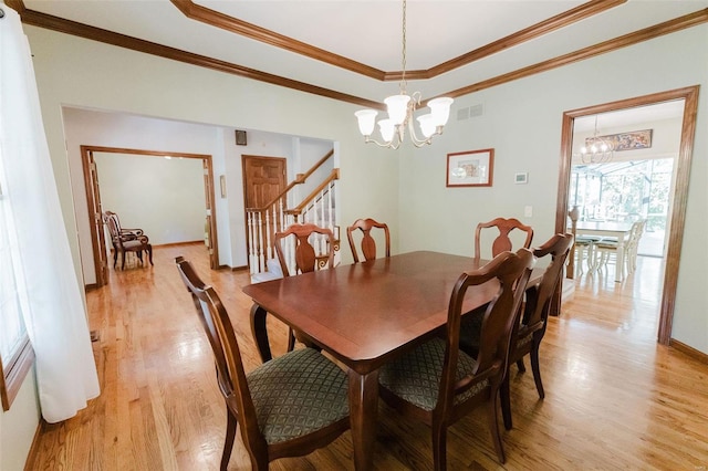 dining room featuring light hardwood / wood-style floors, crown molding, an inviting chandelier, and a tray ceiling