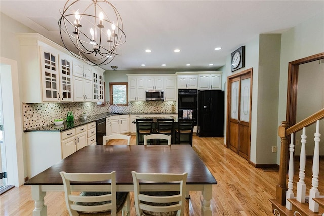 kitchen featuring white cabinets, sink, light hardwood / wood-style floors, black fridge, and hanging light fixtures