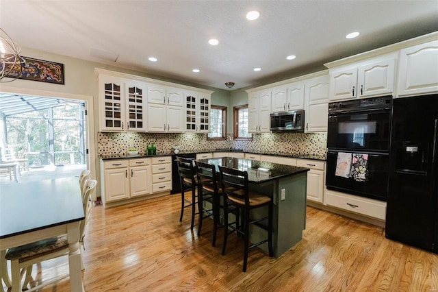 kitchen featuring white cabinetry, black appliances, a breakfast bar, and a healthy amount of sunlight