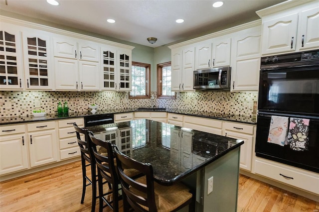 kitchen featuring black appliances, a breakfast bar area, and white cabinets