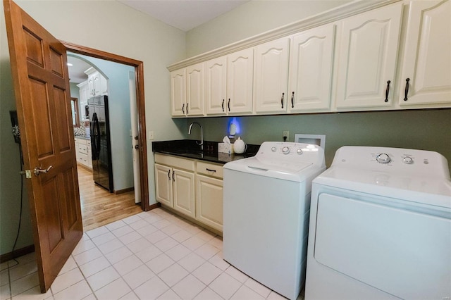 laundry room with washing machine and dryer, sink, light hardwood / wood-style floors, and cabinets