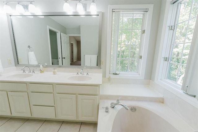 bathroom with tile patterned flooring, a tub to relax in, and vanity