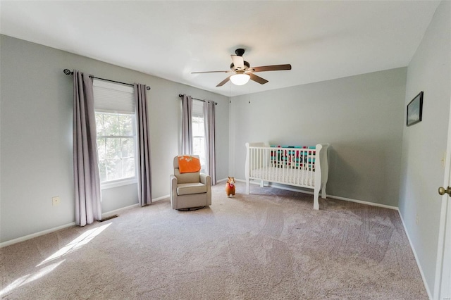 unfurnished bedroom with a crib, carpet flooring, and ceiling fan