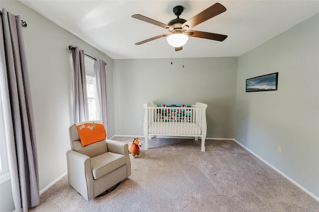 carpeted bedroom featuring a nursery area and ceiling fan