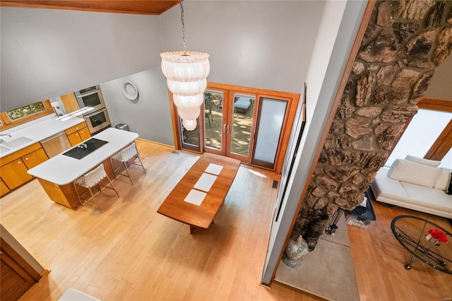 living room with beamed ceiling, an inviting chandelier, light wood-type flooring, and high vaulted ceiling