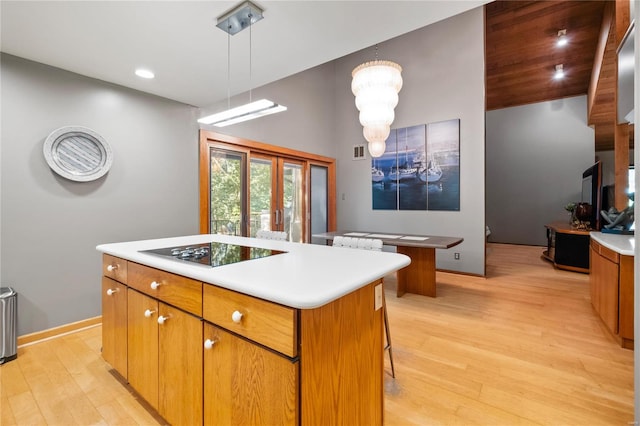 kitchen with a kitchen island, decorative light fixtures, light hardwood / wood-style flooring, and electric cooktop