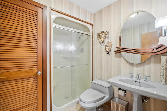 bathroom featuring a shower with door and toilet