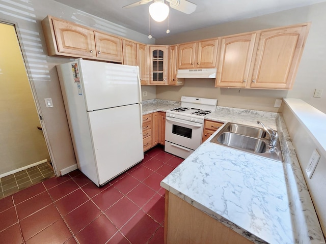 kitchen with light brown cabinets, dark tile patterned flooring, sink, and white appliances