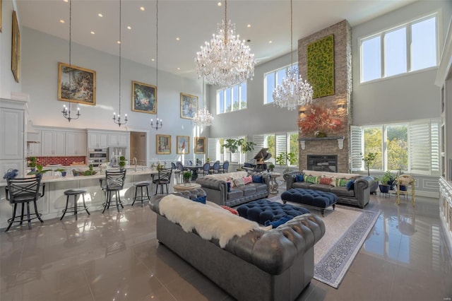 living room featuring a stone fireplace, a high ceiling, an inviting chandelier, and sink