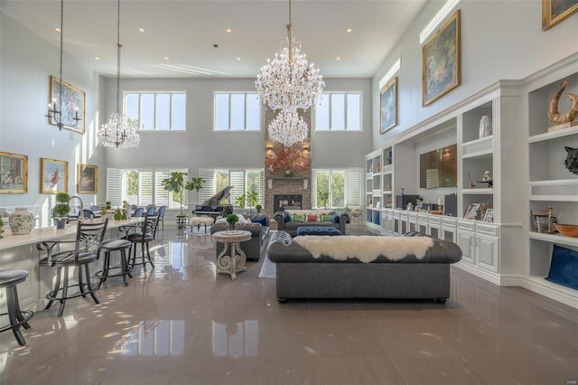 living room featuring a fireplace, a towering ceiling, a chandelier, and built in shelves