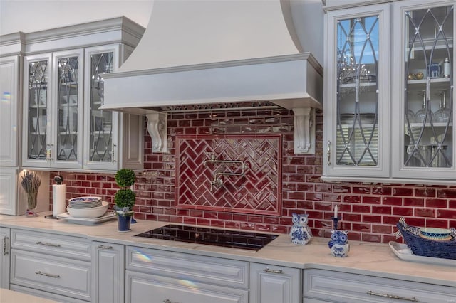 bar with black stovetop, decorative backsplash, and custom exhaust hood