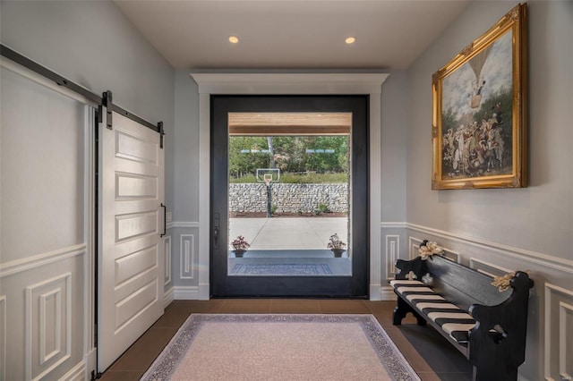 doorway to outside with dark tile patterned flooring and a barn door