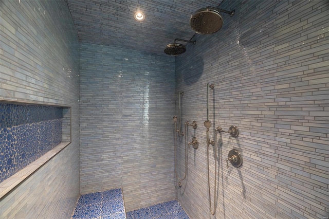 bathroom with a tile shower and tile walls