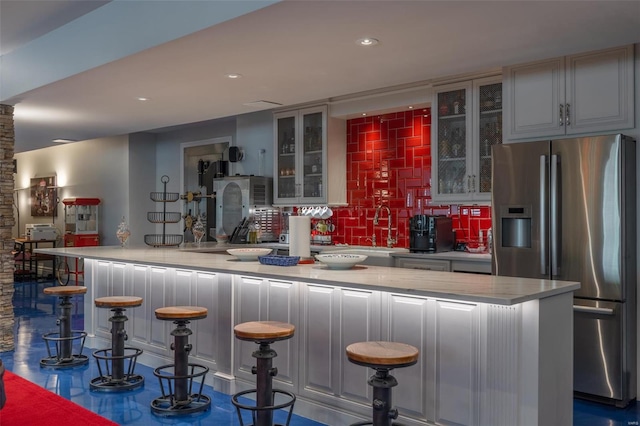 bar featuring decorative backsplash, gray cabinetry, stainless steel fridge with ice dispenser, and sink