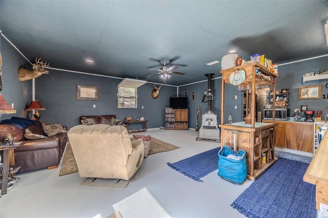 living room featuring a wood stove, ceiling fan, and concrete floors