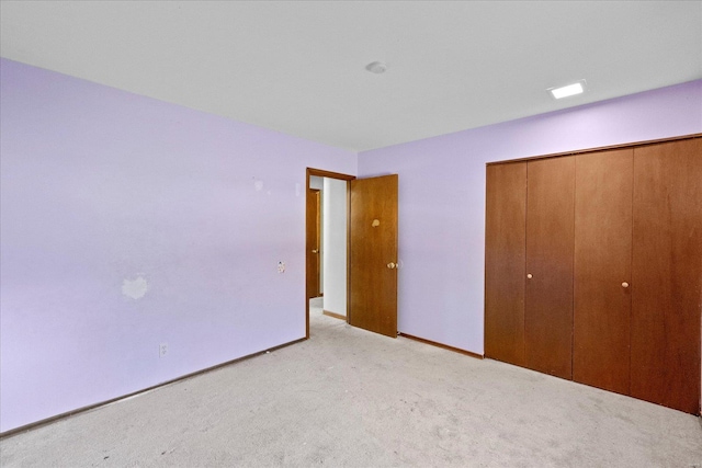 unfurnished bedroom featuring a closet and light colored carpet