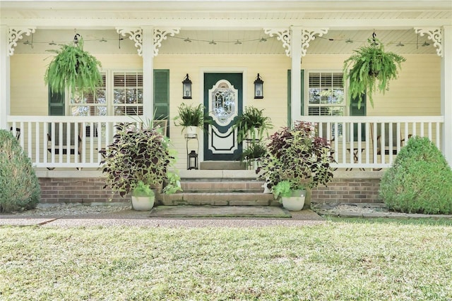 view of exterior entry with covered porch and a yard