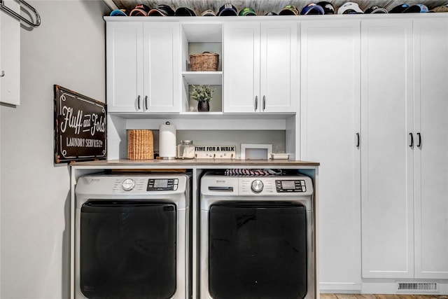 laundry room featuring washer and dryer, visible vents, and cabinet space