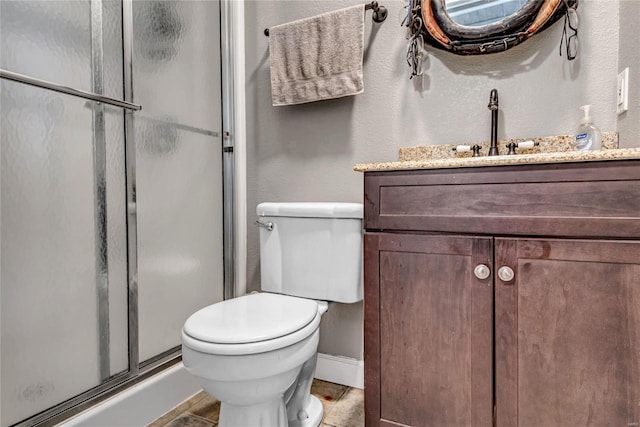 full bathroom featuring a stall shower, vanity, and toilet