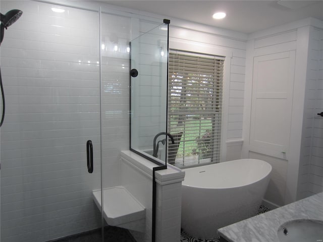 bathroom featuring a stall shower, a soaking tub, vanity, and recessed lighting