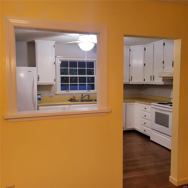 kitchen featuring white appliances, dark wood-type flooring, white cabinets, sink, and a textured ceiling