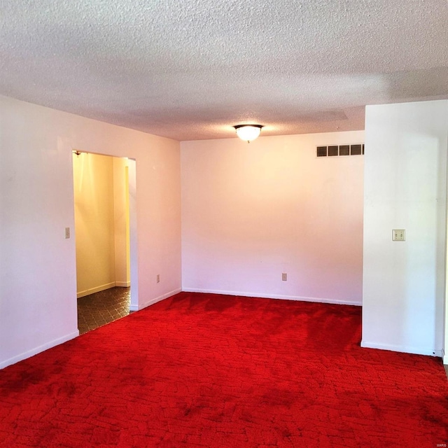 empty room featuring a textured ceiling and dark carpet