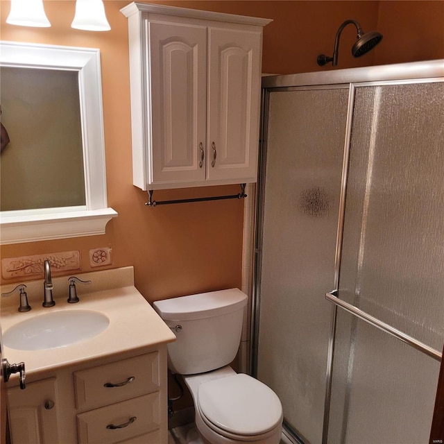 bathroom with vanity, toilet, and a shower with shower door