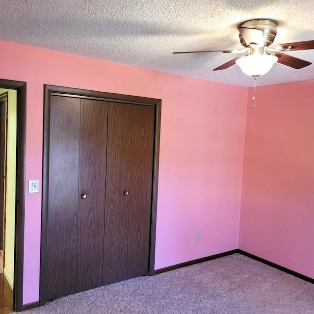 unfurnished bedroom with ceiling fan, a closet, light colored carpet, and a textured ceiling