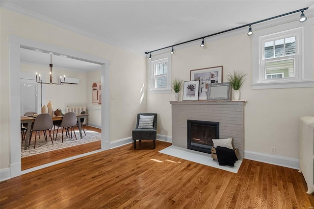 sitting room with a wall mounted air conditioner, rail lighting, a fireplace, wood-type flooring, and a chandelier