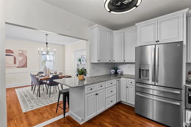 kitchen with a breakfast bar, white cabinetry, light stone counters, kitchen peninsula, and stainless steel appliances