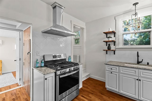 kitchen with gas range, sink, wall chimney range hood, dark hardwood / wood-style floors, and decorative backsplash