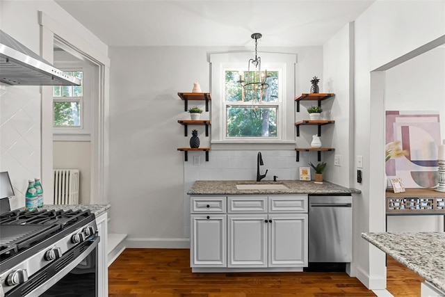 kitchen with decorative backsplash, radiator, stainless steel gas range, sink, and pendant lighting