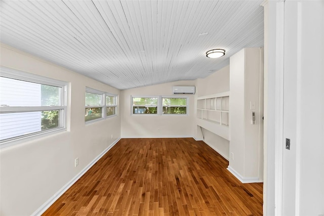 interior space with hardwood / wood-style floors, vaulted ceiling, a wall mounted AC, and plenty of natural light