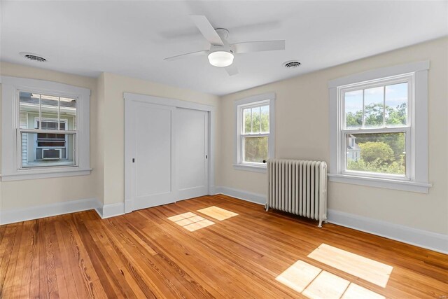 unfurnished bedroom featuring a closet, light hardwood / wood-style flooring, radiator, and ceiling fan