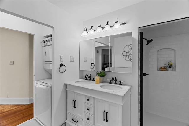 bathroom featuring walk in shower, wood-type flooring, vanity, and stacked washer / dryer