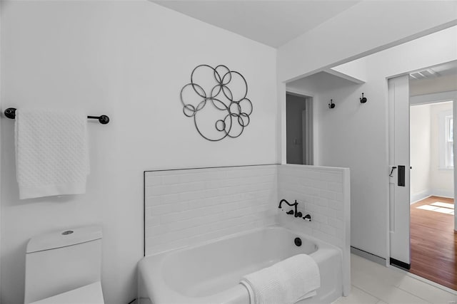 bathroom with tile patterned floors, toilet, and a bath