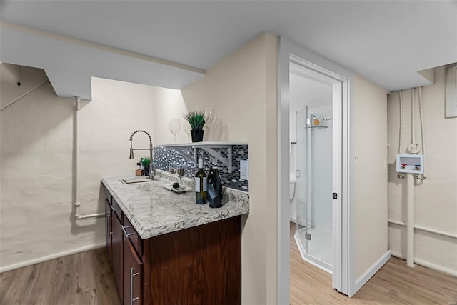 interior space with dark brown cabinetry, decorative backsplash, light hardwood / wood-style flooring, and sink