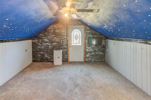 additional living space featuring ceiling fan, carpet floors, lofted ceiling, and wooden walls