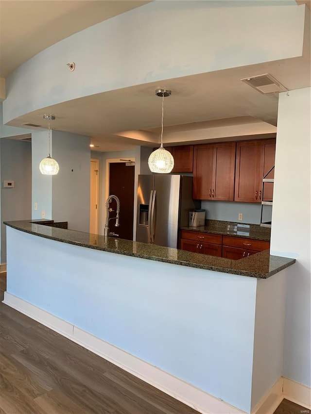 kitchen with stainless steel fridge with ice dispenser, dark stone countertops, dark wood-type flooring, and pendant lighting