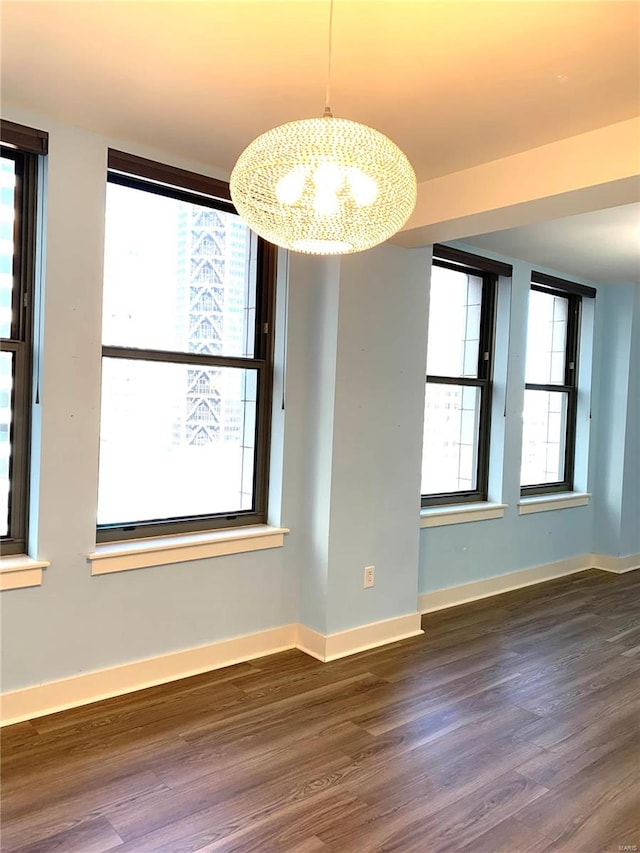 unfurnished dining area with dark wood-type flooring, an inviting chandelier, and plenty of natural light