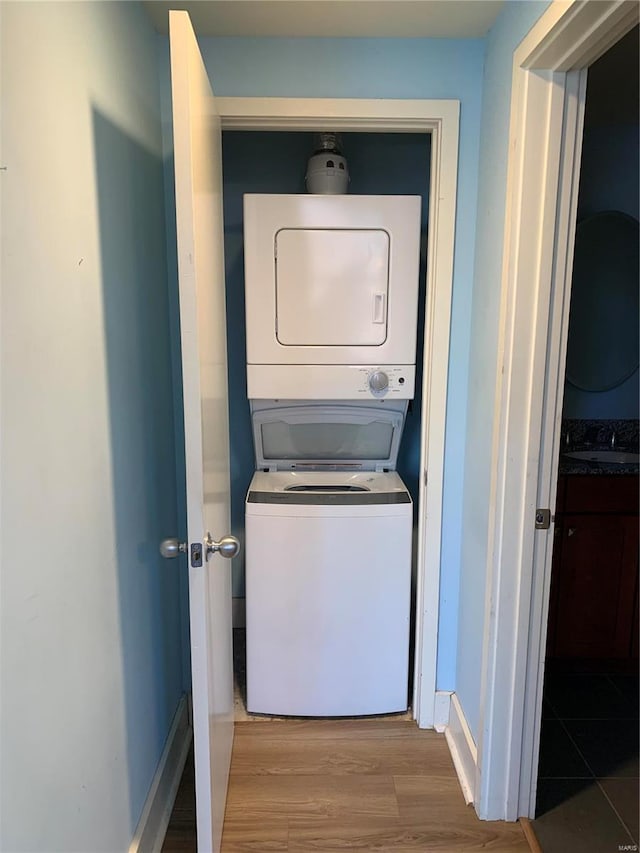 laundry area featuring hardwood / wood-style flooring, stacked washer and dryer, and sink