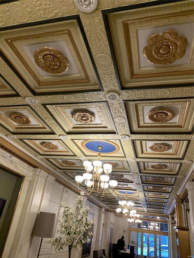 details with ornamental molding, coffered ceiling, and an inviting chandelier