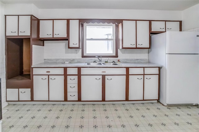 kitchen featuring white cabinets, sink, backsplash, and white fridge