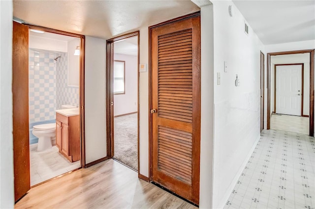 hall with tile walls and light wood-type flooring