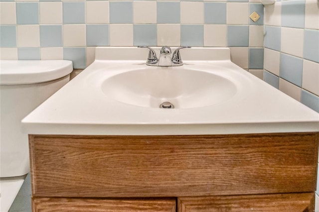 bathroom featuring vanity, tile walls, and toilet