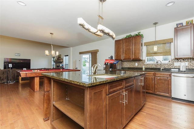 kitchen with pendant lighting, tasteful backsplash, dishwasher, an island with sink, and sink