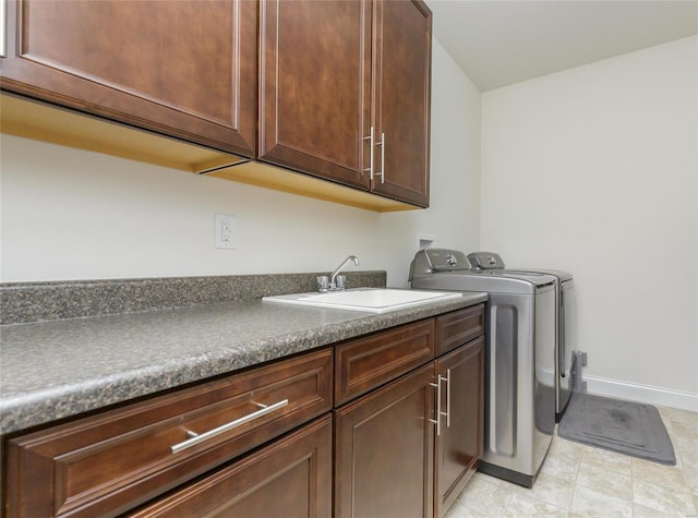 clothes washing area with sink, washer and clothes dryer, and cabinets