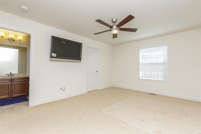 unfurnished room with sink, light colored carpet, and ceiling fan