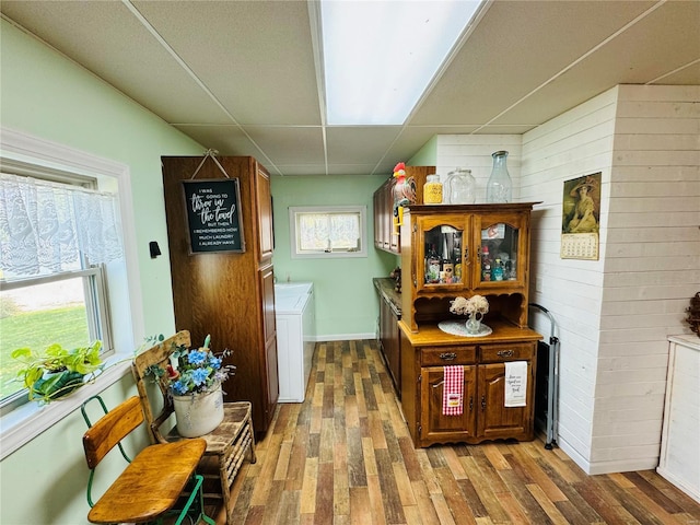 corridor with hardwood / wood-style flooring, washer and clothes dryer, and wood walls