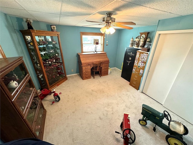 carpeted office space featuring ceiling fan and a drop ceiling